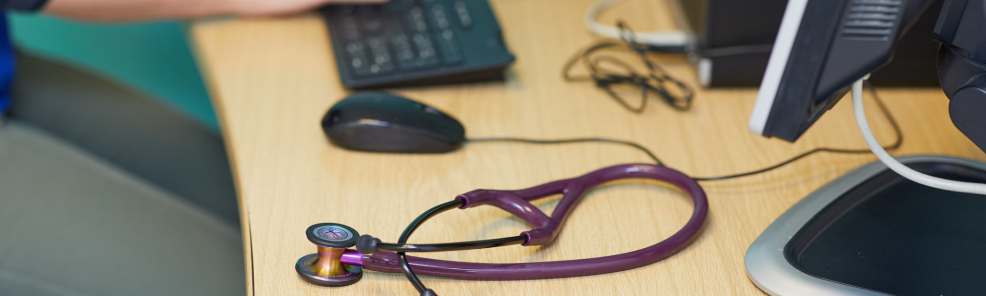 A photo showing a work desk with a computer and stethoscope