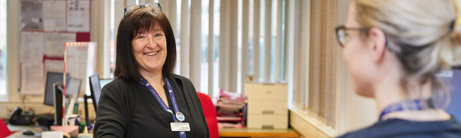 A photo showing a receptionist giving a patient a prescription at Rawcliffe surgery