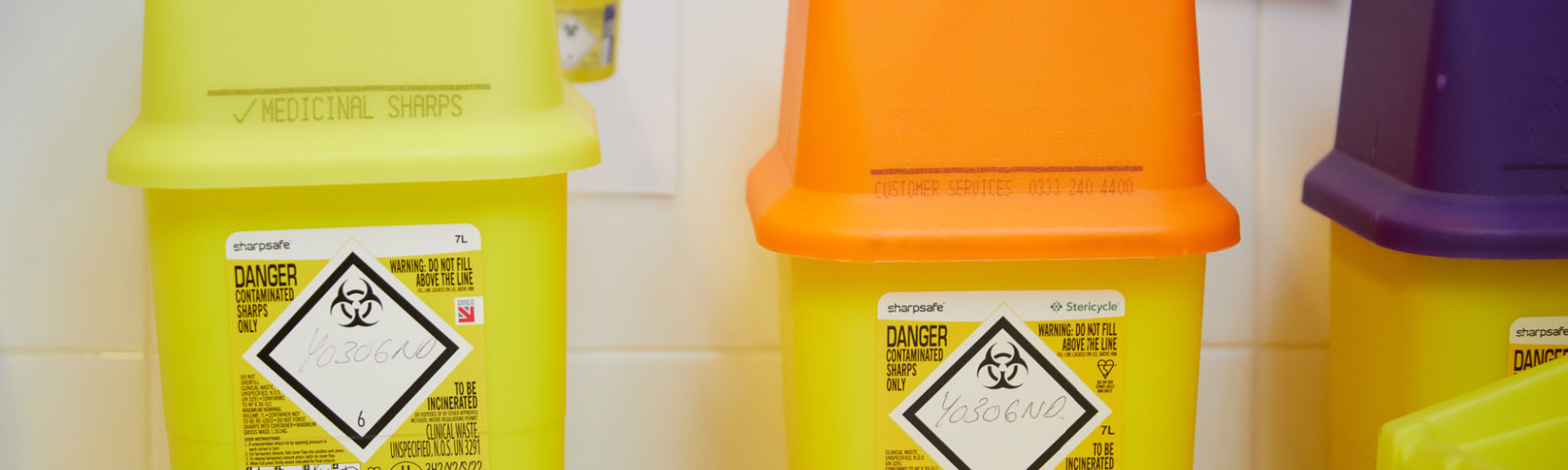 A photo showing three sharps bins