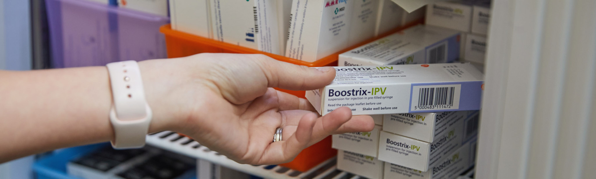 A photo showing a clinician getting a vaccine out of the fridge