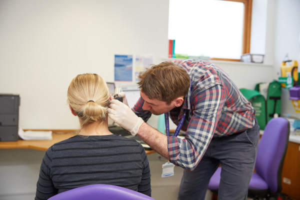 A photo showing Dr Knight checking a patients ears