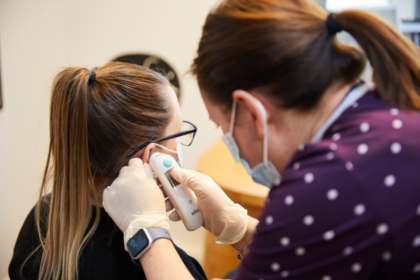 A photo showing a clinician checking a patients temperature