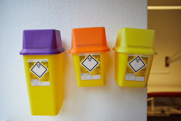 A photo showing three sharps bins on the wall