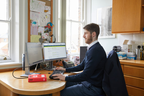 A photo showing a pharmacist using the computer